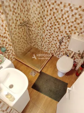Smaller bathroom with a shower cabin, sink, and toilet. - image 8