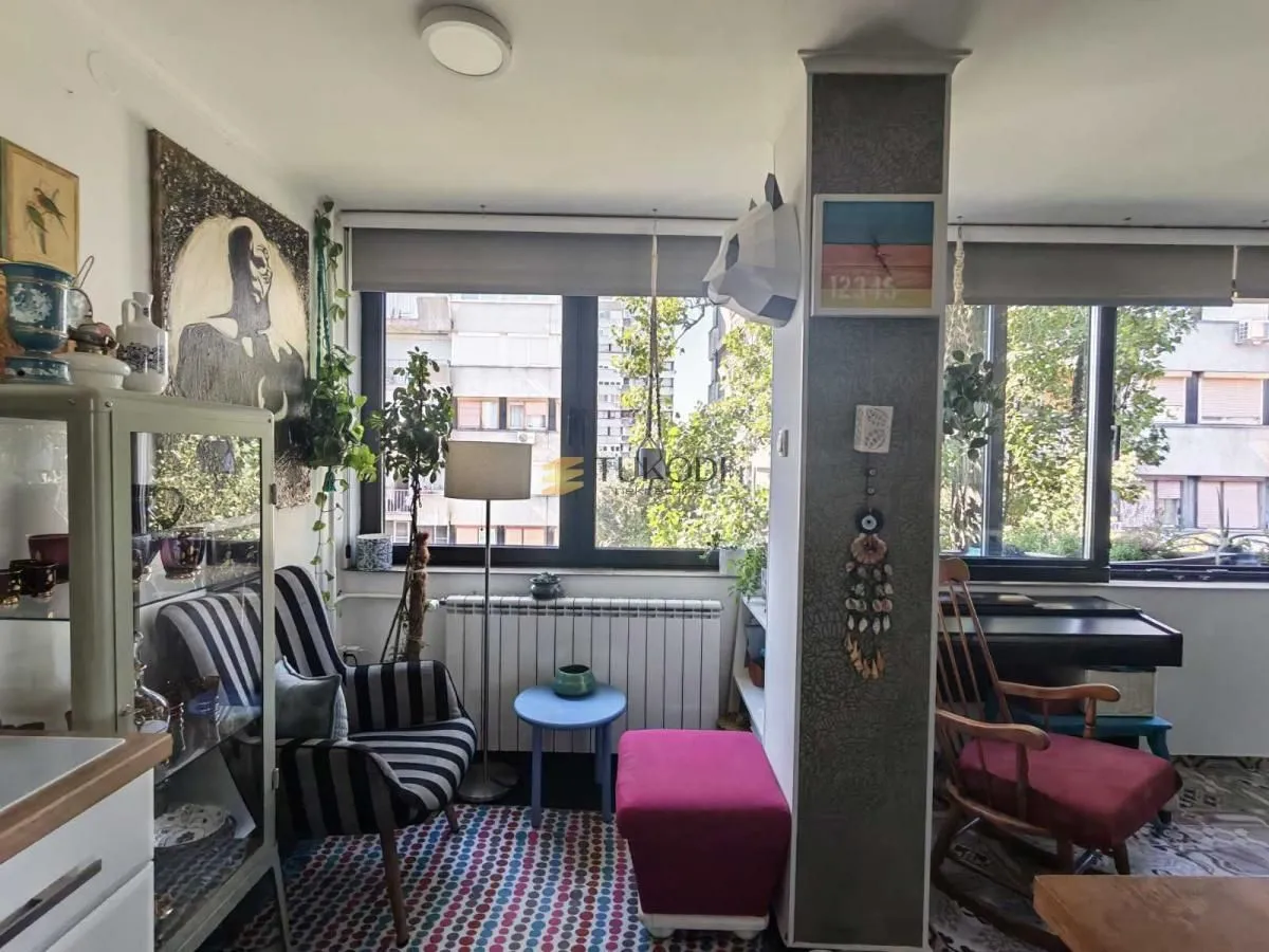 Dnevni boravak sa garniturom, velikim prozorima i dekorativnim detaljima.