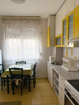 Kitchen with white and yellow cabinetry and a dining table by the window. - image 3