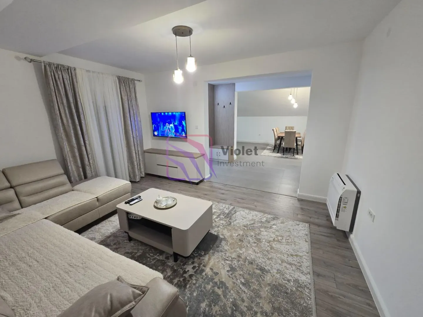 Living room with a sofa, coffee table and TV, with a view of the dining area.