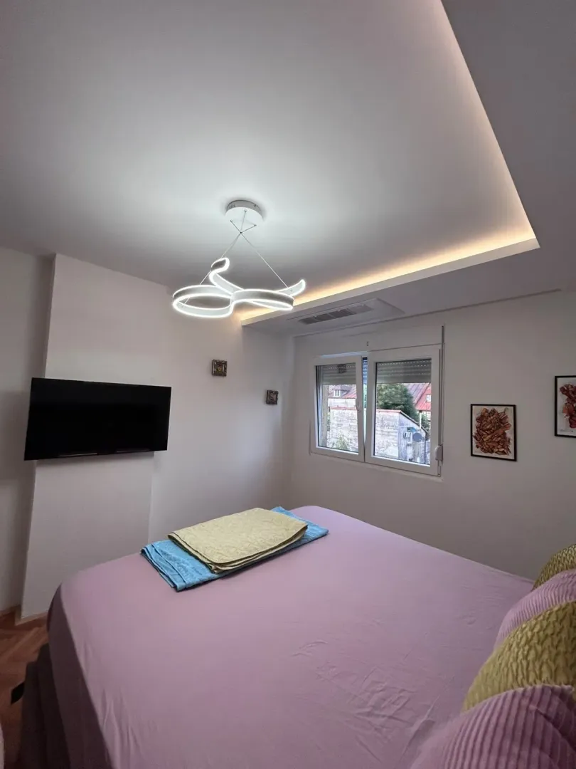 Tidy bedroom with a double bed, TV, and modern lighting.