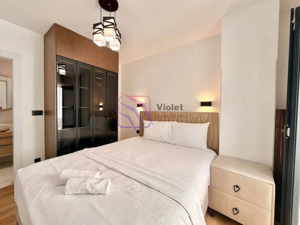 Furnished bedroom with a double bed, wardrobe, and a nightstand.