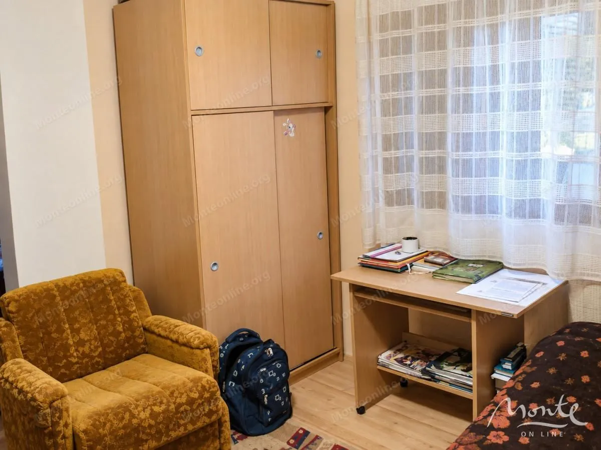 Small bedroom with a wardrobe, desk, and armchair.