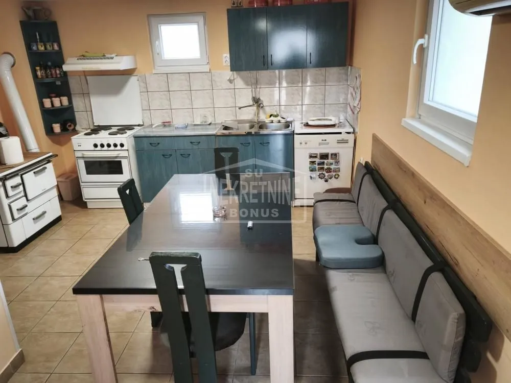 Kuhinja sa trpezarijom opremljena elementima i stolom za ručavanje.