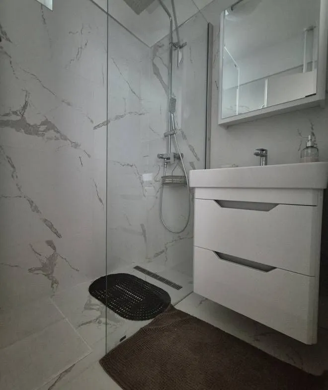 Modern bathroom with a walk-in shower and a white vanity unit.