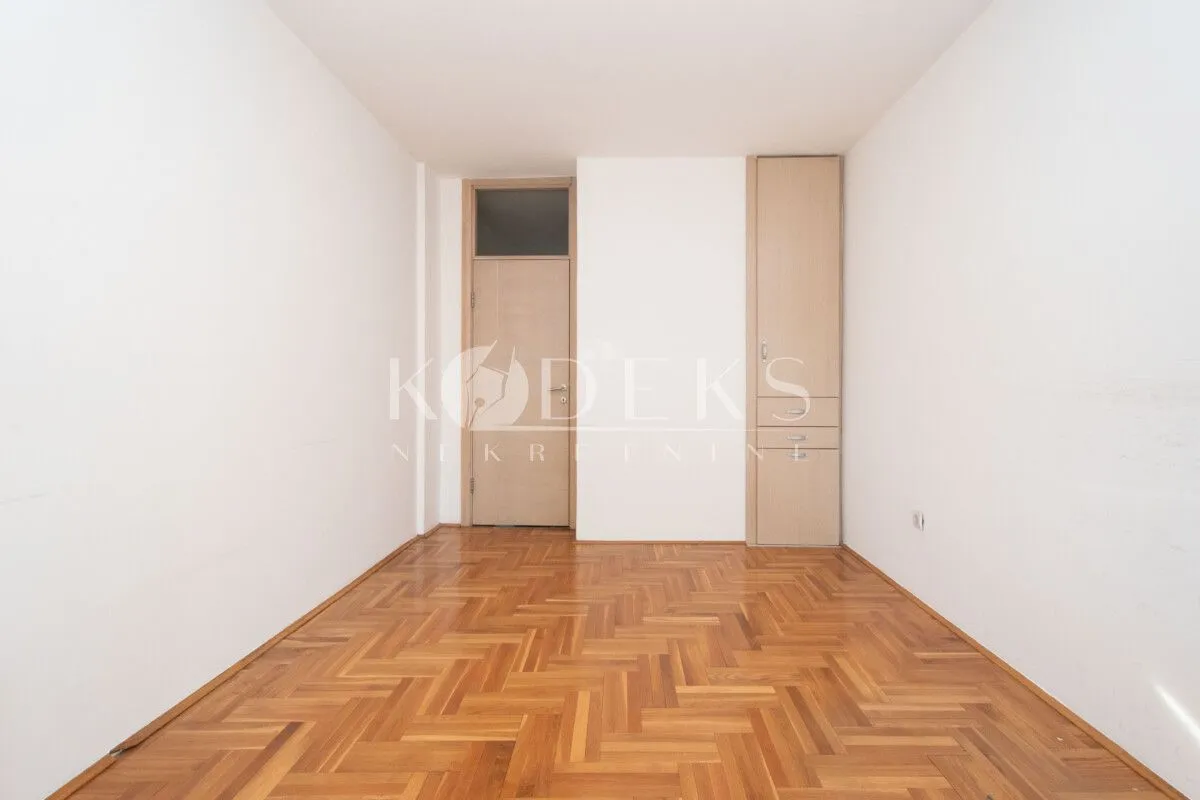 Empty room with wooden parquet flooring and a built-in closet.