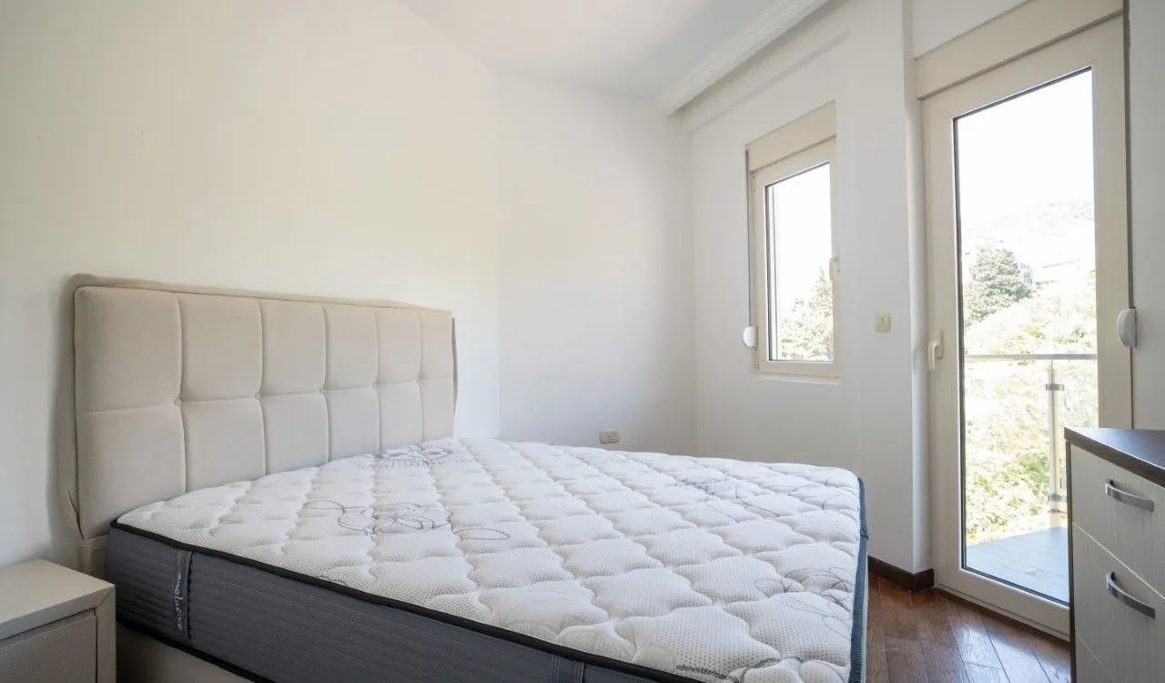 Svjetla spavaća soba sa bračnim krevetom i izlazom na terasu.