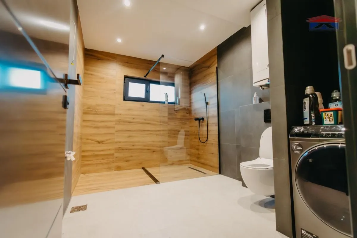 Moderno kupatilo sa tuš kabinom, WC šoljom i veš mašinom.