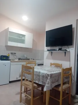 Manja kuhinja sa trpezarijskim stolom i televizorom na zidu. - image 3