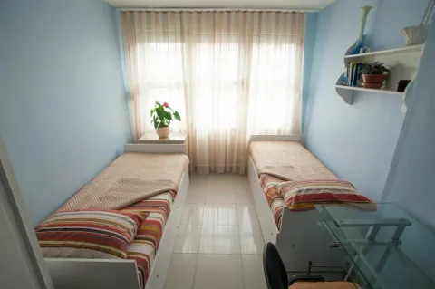 Children's bedroom with two single beds and a curtained window. - image 10
