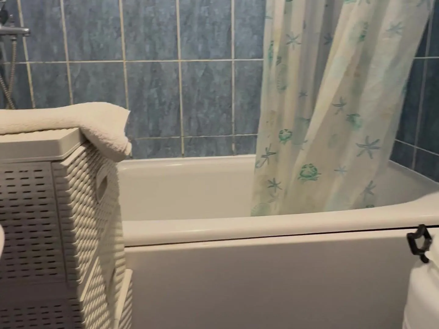 Bathroom with a bathtub and blue wall tiles.