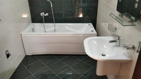 Kupatilo opremljeno bijelom kadom i umivaonikom. - image 26