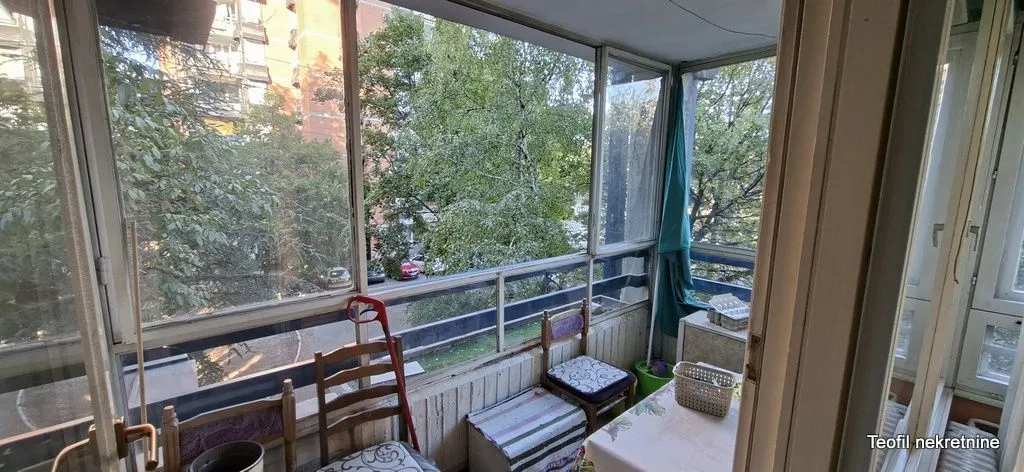 Zastakljeni balkon sa pogledom na drveće i ulicu.