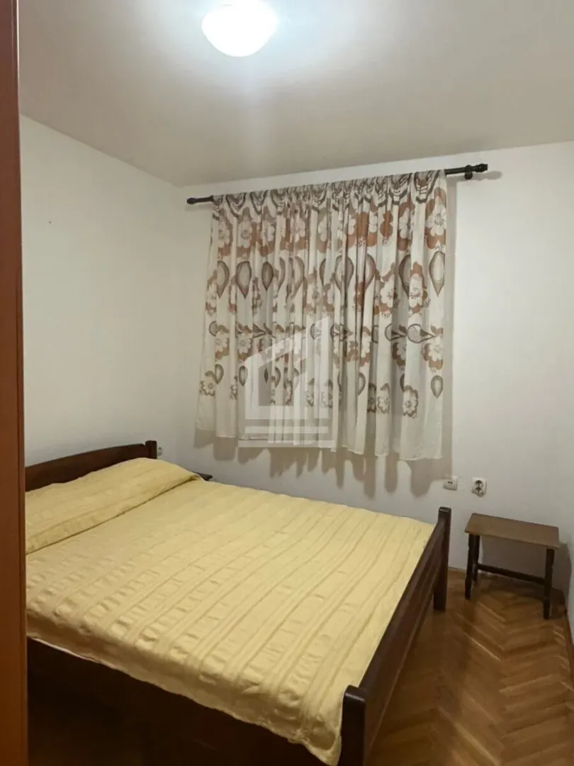 Bedroom with a double bed and a window with curtains.