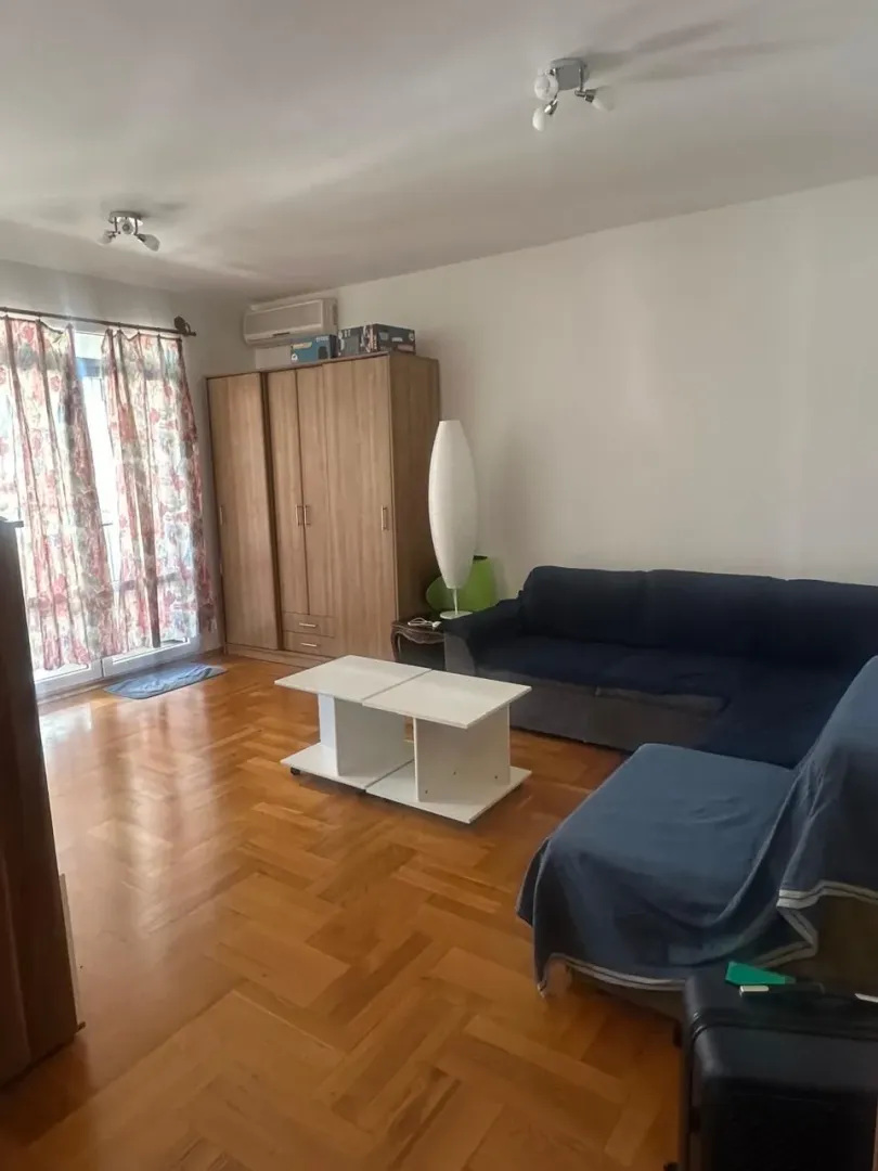Dnevna soba sa garniturom, ormarom, stočićem i parketom.