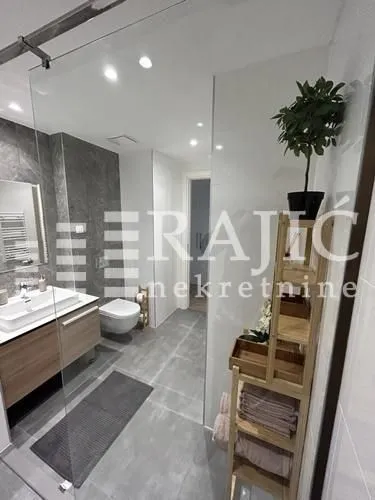 Modern bathroom with a walk-in shower, washbasin, and toilet.