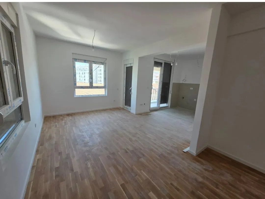 Empty living room with wooden flooring and white walls.