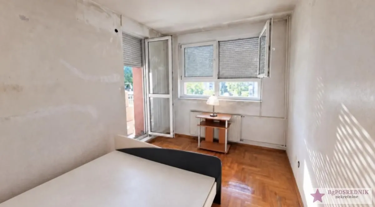 Small bedroom with a bed, parquet flooring, and access to the terrace.