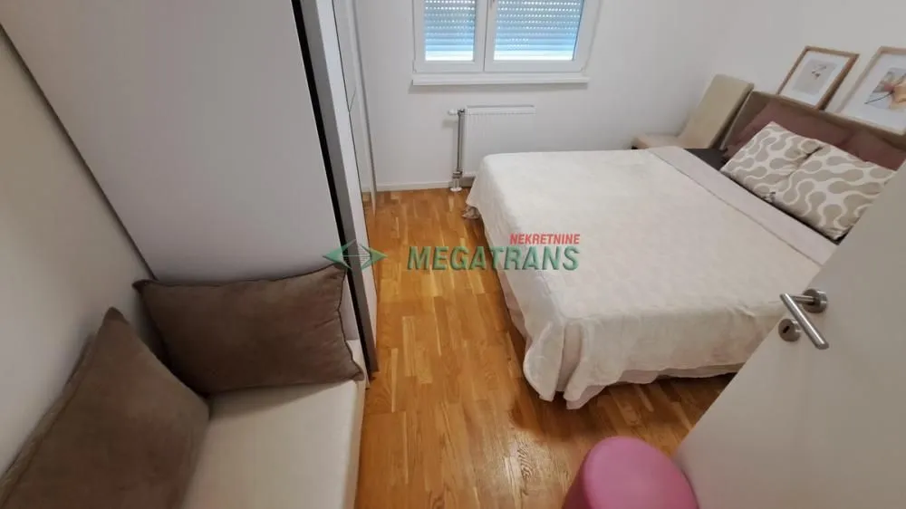 Nameštena spavaća soba sa bračnim krevetom, ormarom i prozorom.