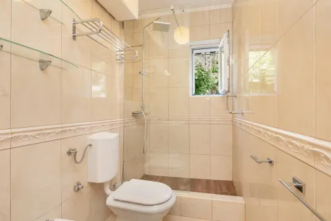 Kompaktno kupatilo sa tuš kabinom obloženo bež pločicama. - image 7