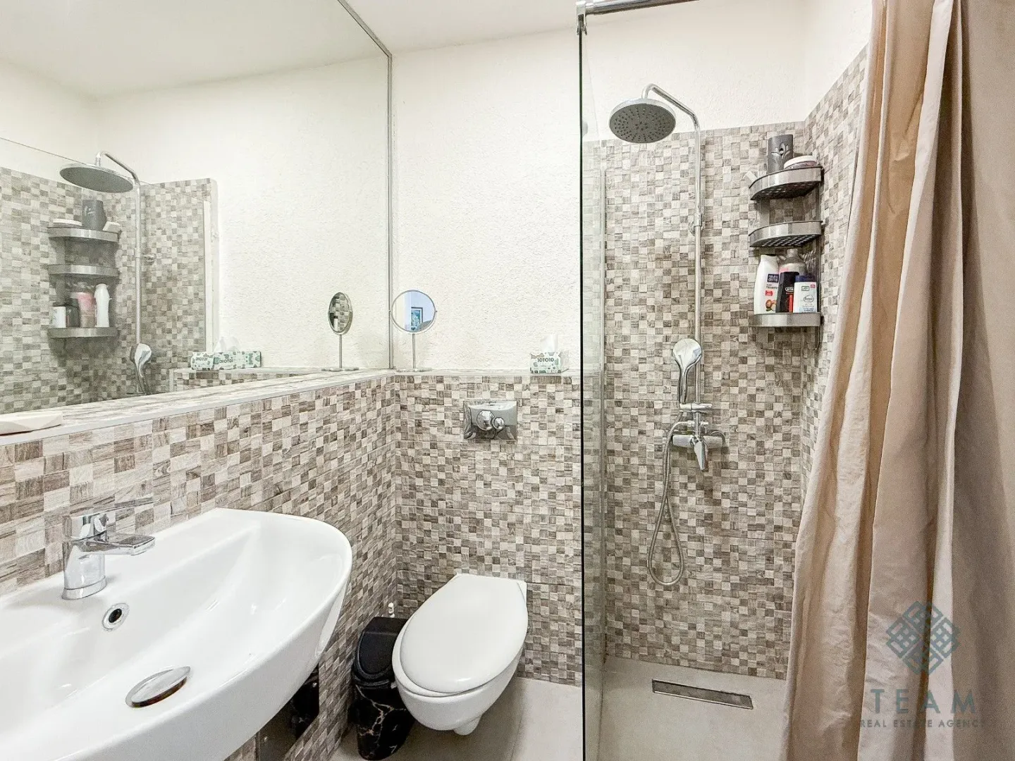 Compact bathroom with a shower cabin, washbasin, and toilet.