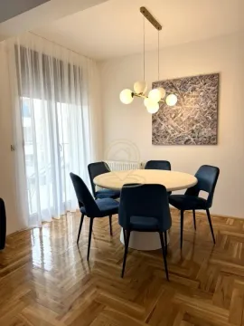 Dining area with a round table, blue chairs, and a chandelier. - image 4