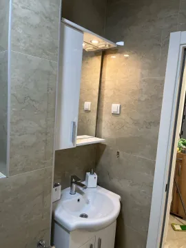 Moderno kupatilo sa bijelim lavaboom, ogledalom i ormarićem. - image 10