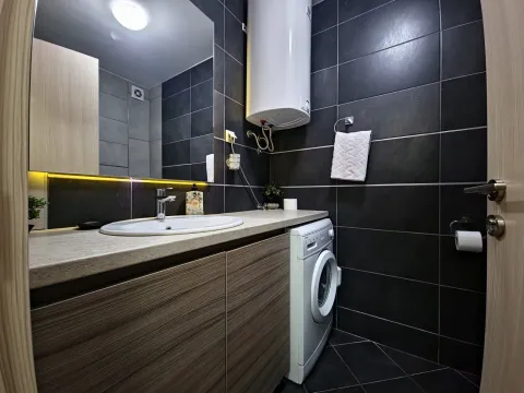 Modernly equipped bathroom with a washbasin, mirror, and washing machine. - image 4