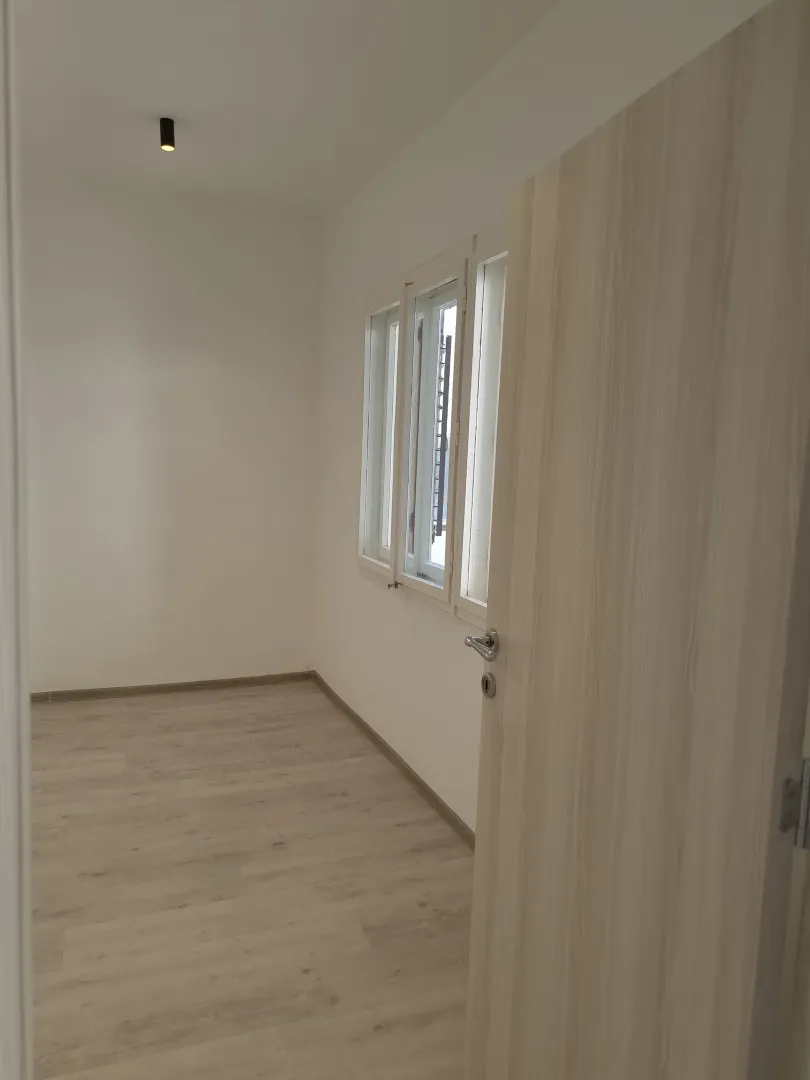 Empty room with light laminate flooring and an open door.