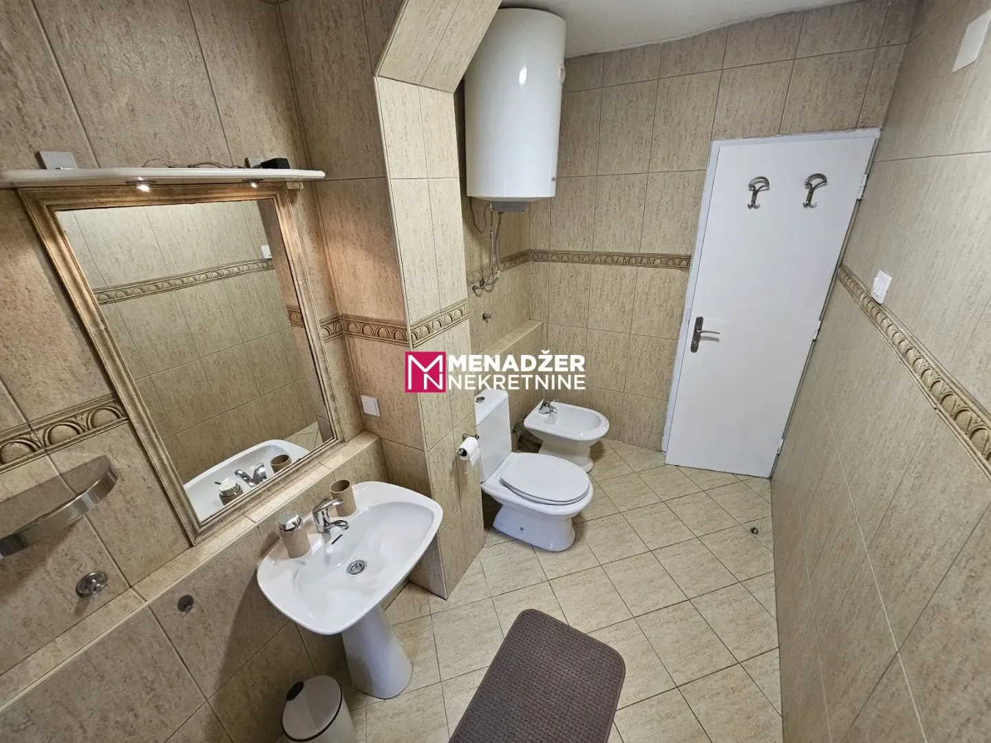 Bathroom equipped with sanitary fixtures, a sink with a mirror, and tiled walls.