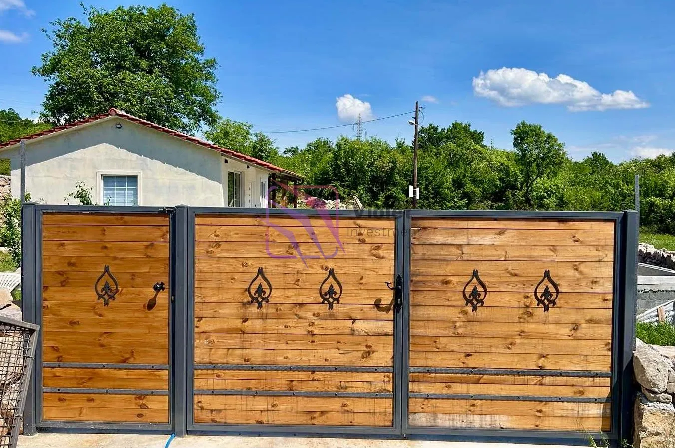Wooden yard gate with a metal frame and part of the house in the background.