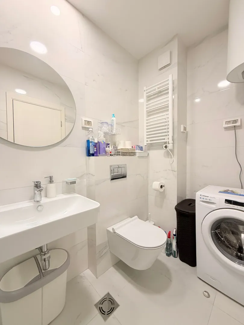 Moderne opremljeno kupatilo sa umivaonikom, WC šoljom i veš mašinom.