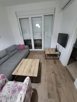 Living room with a sofa, coffee tables and a television. - image 2