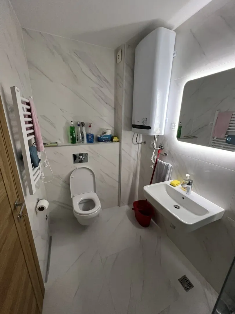 Modern bathroom with light tiles, a washbasin, and a toilet.