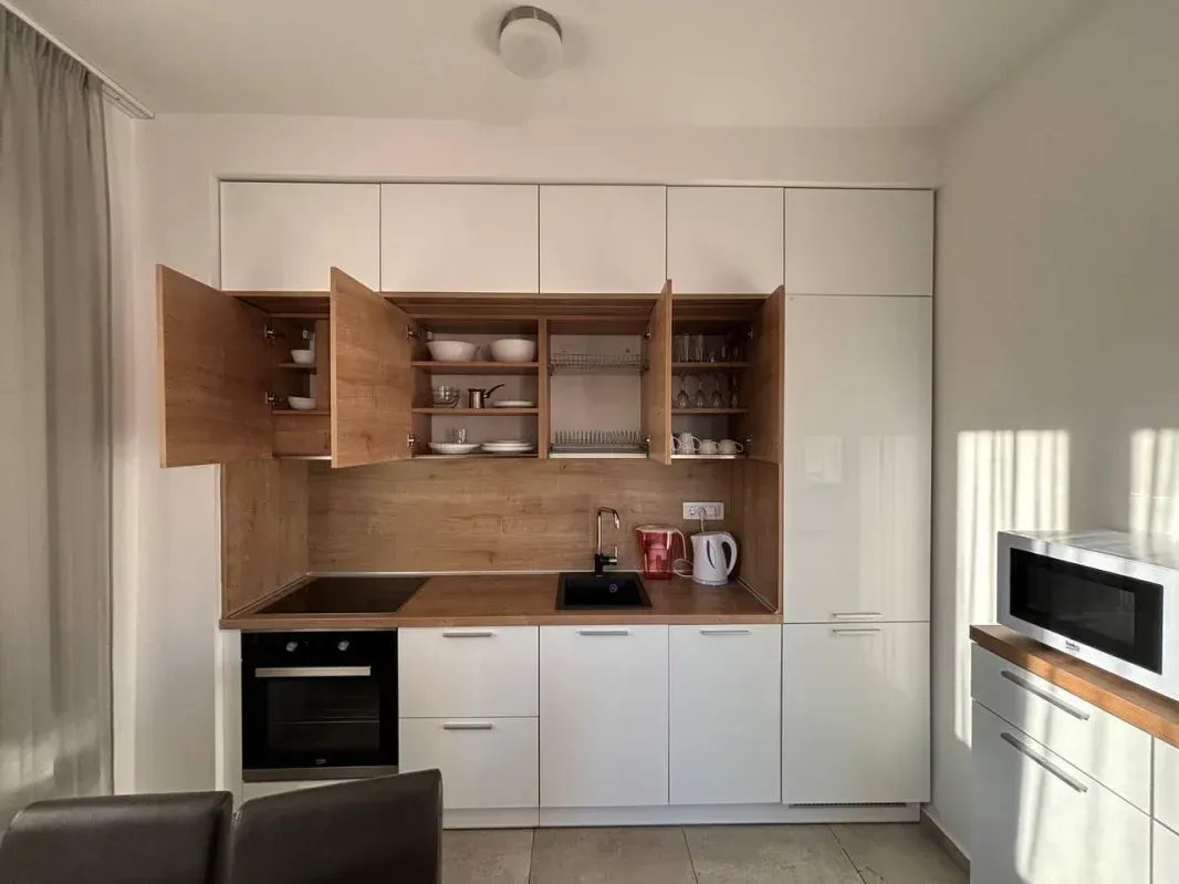 Modern kitchen with white and wood-finish cabinetry.
