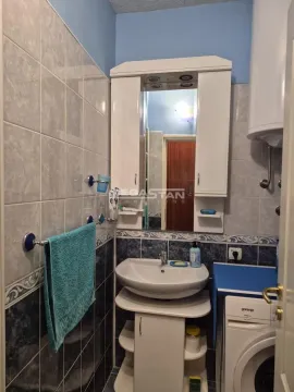 Small bathroom with a washbasin, mirror, cabinet, and washing machine. - image 11