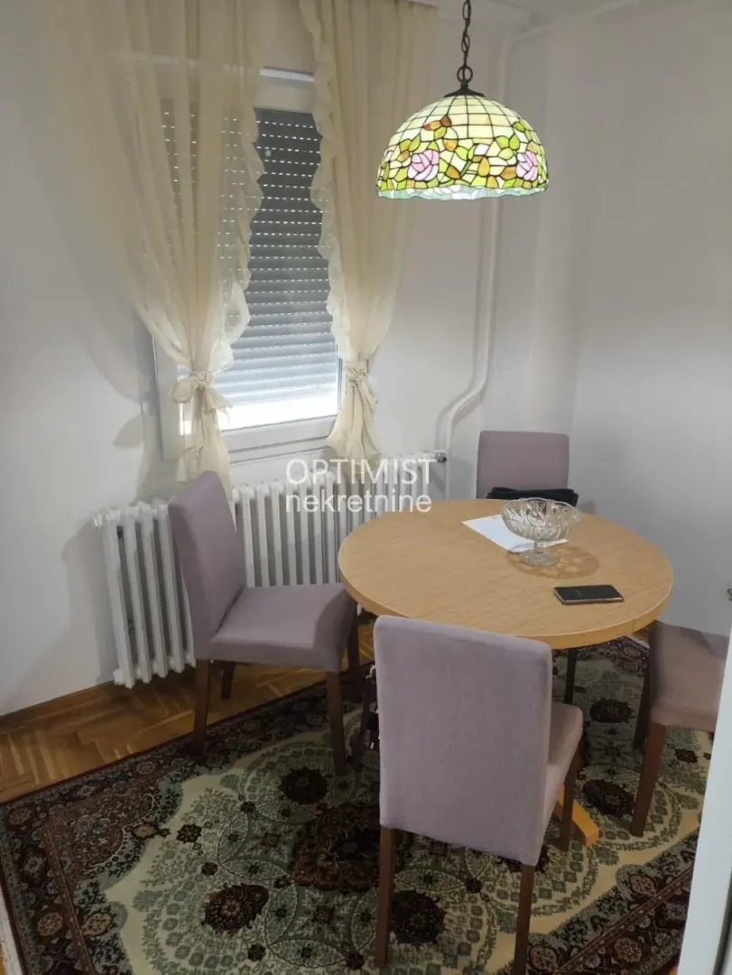 Dining area with a table, four chairs, and a decorative lamp.