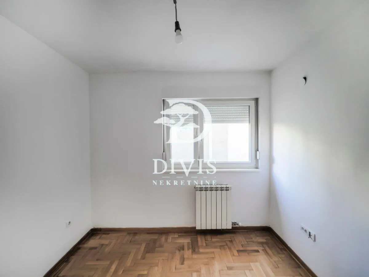 Empty room with white walls, parquet flooring, and a single window.