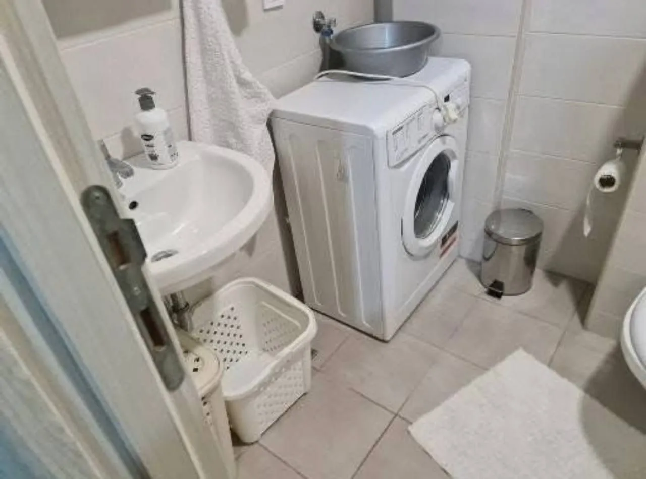 Manje kupatilo sa umivaonikom, veš mašinom i toaletom.