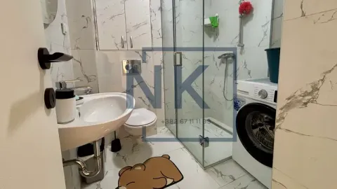 Bathroom with a shower cabin, washbasin, and washing machine. - image 10