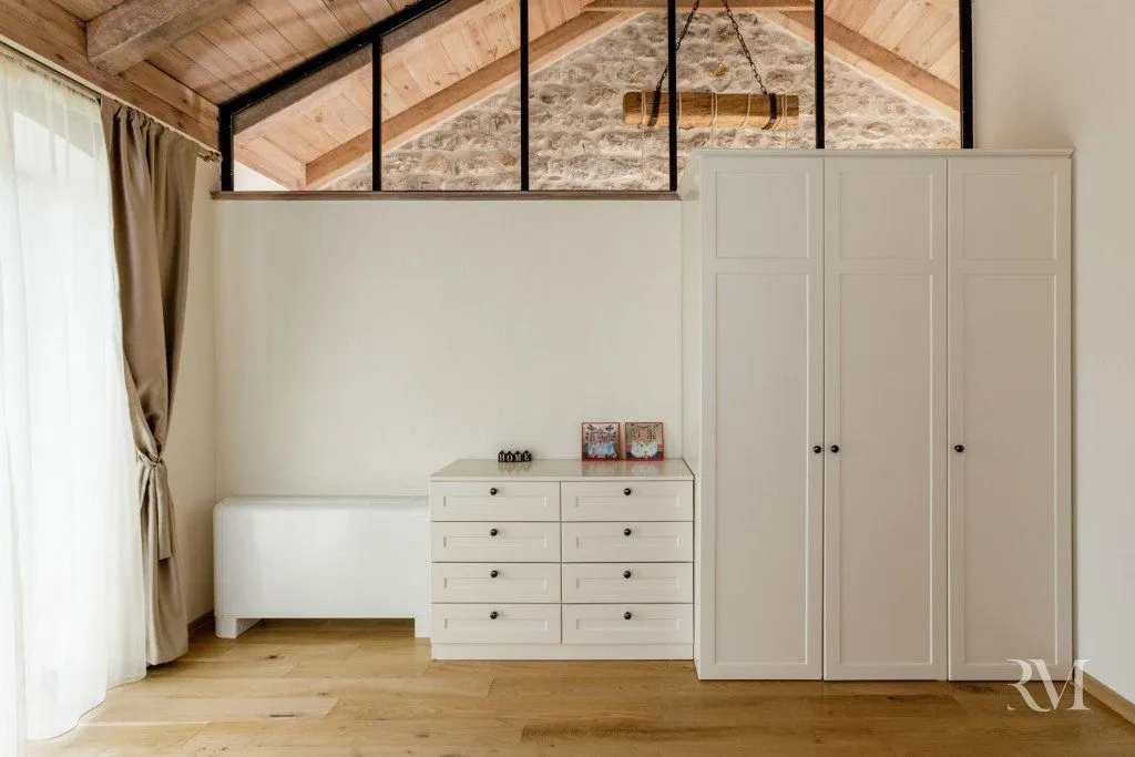Bright bedroom area with wooden flooring, a white wardrobe, and a chest of drawers.