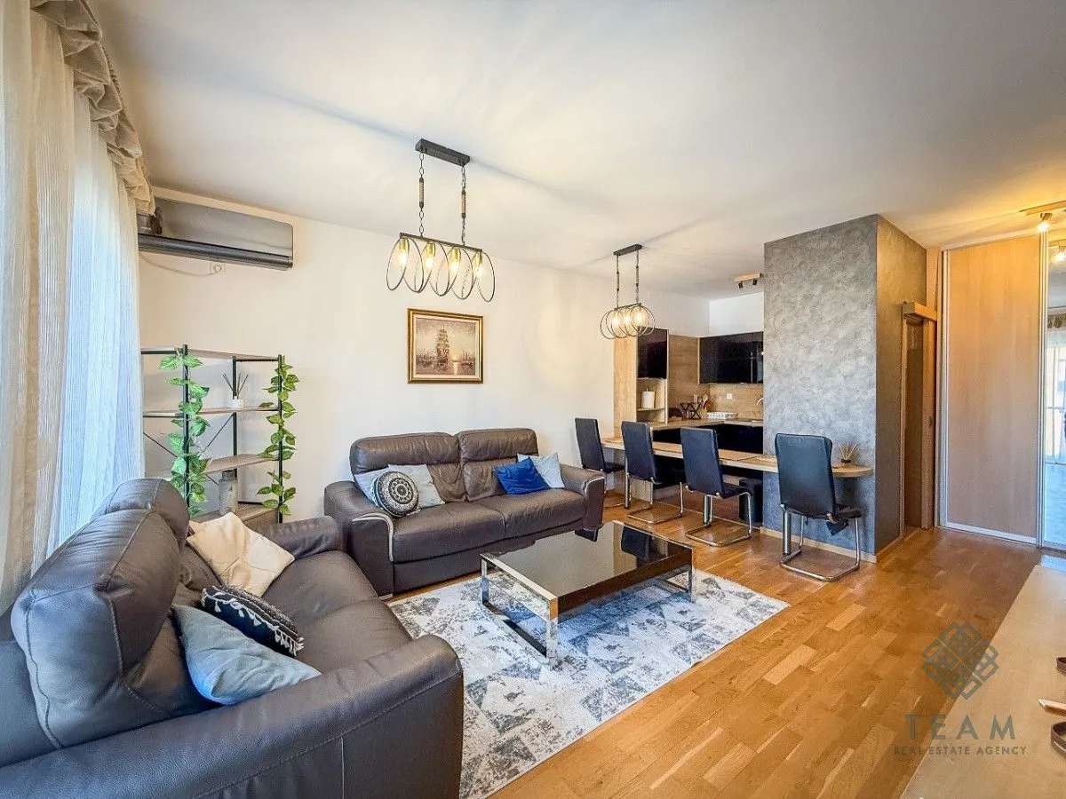Living room with a sofa, coffee table, and a view of the kitchen with a bar.