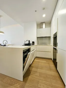 Modern white kitchen with an island and wooden flooring. - image 6