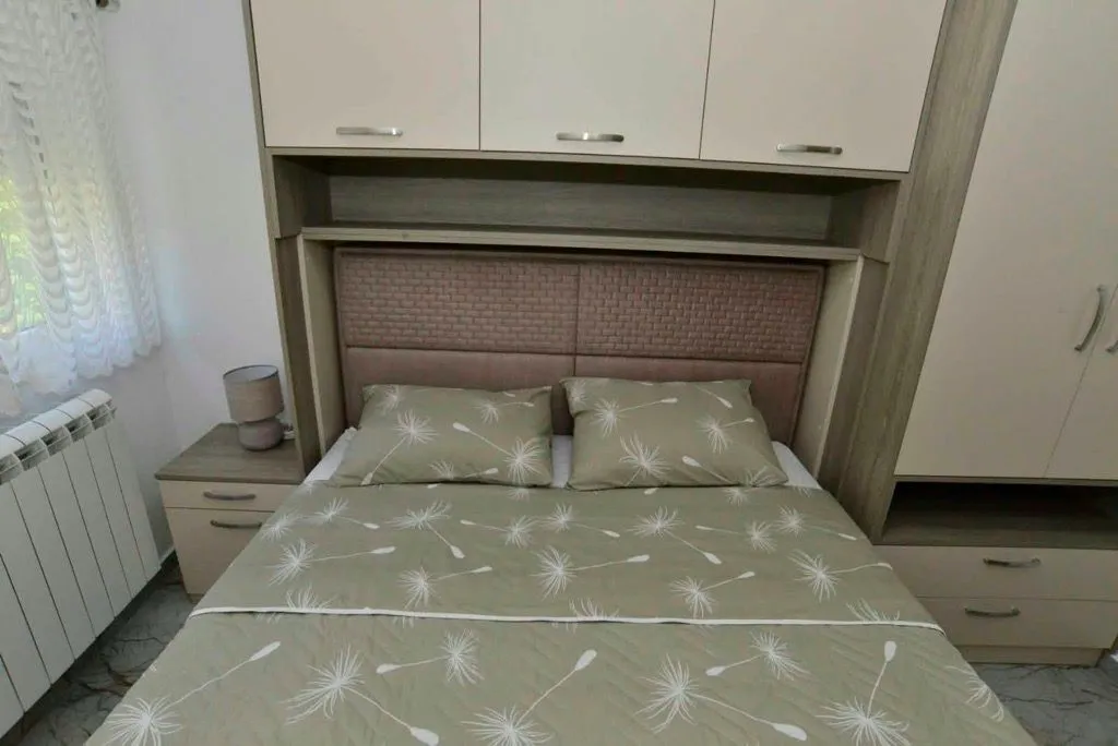 Namještena spavaća soba sa bračnim krevetom i ugradnim ormarima.