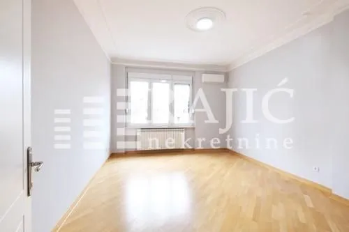 Empty bright room with wooden flooring and a window.