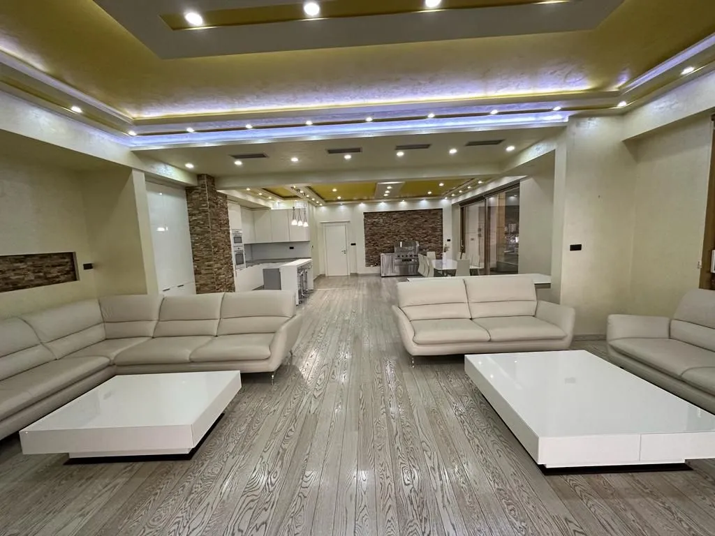 Spacious living room with seating area and coffee tables, connected to the dining area and kitchen.