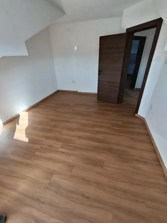 Prazna soba sa laminatom i vratima.
