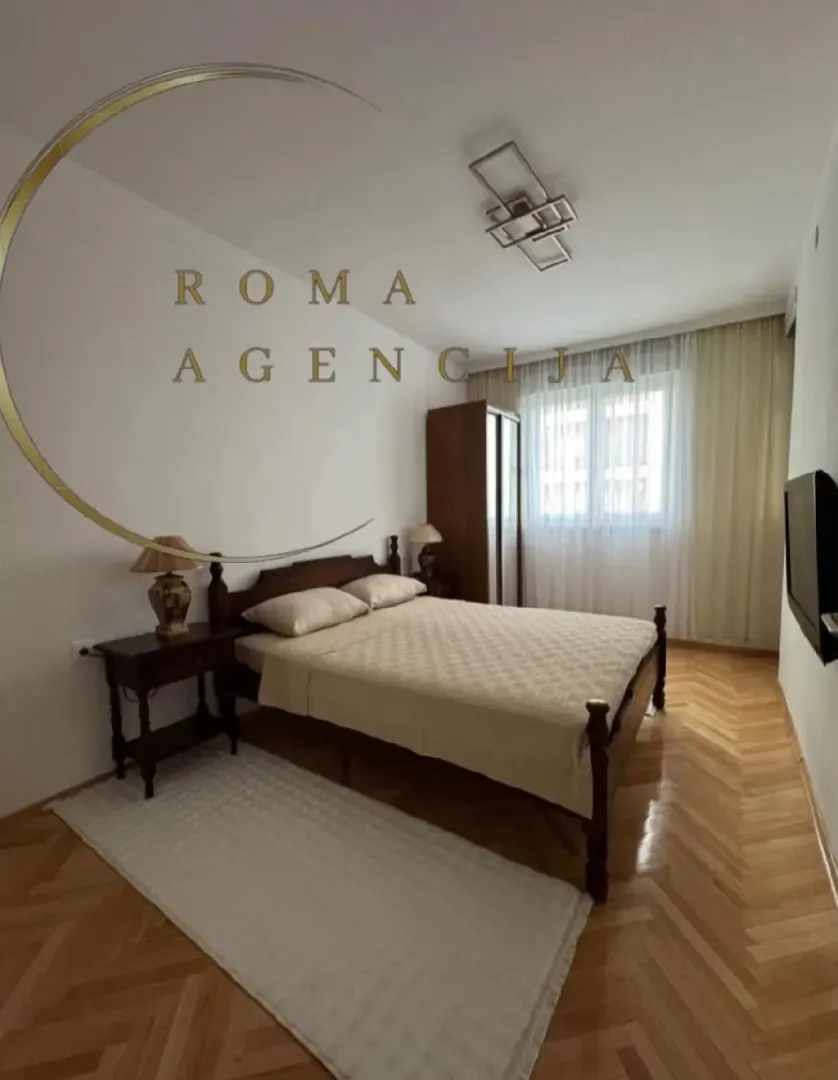 Furnished bedroom with a double bed, wardrobe, and parquet flooring.