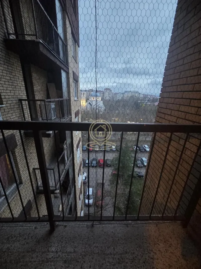 Pogled sa balkona na okolne zgrade i parking.