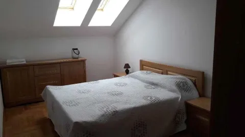Svijetla spavaća soba u potkrovlju sa drvenim namještajem. - image 3